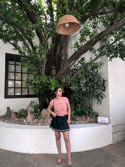A casual look with a pink t-shirt and a black tennis skirt.