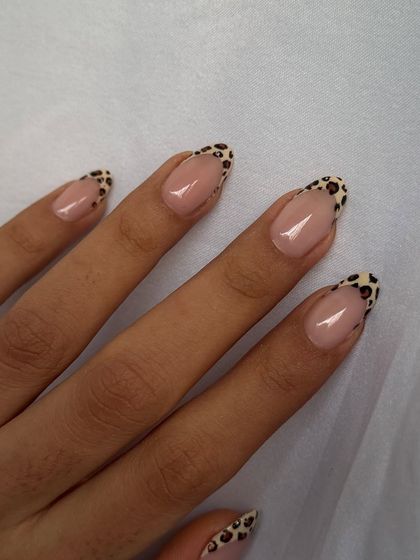 A full view of the sophisticated leopard print French manicure on elegant oval-shaped nails.