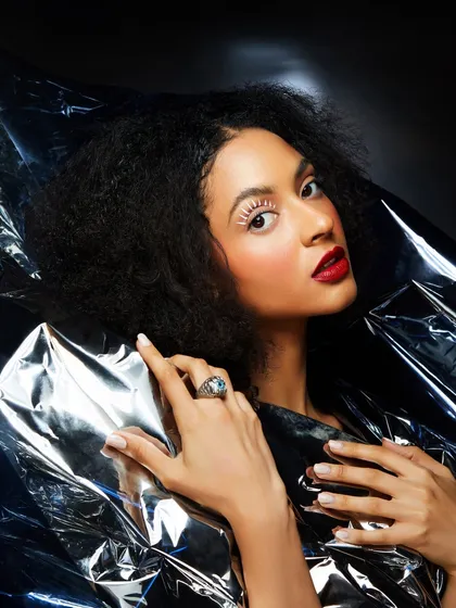 A dramatic look with white lashes and a bold red lip, set against a metallic silver background for a high-fashion feel.