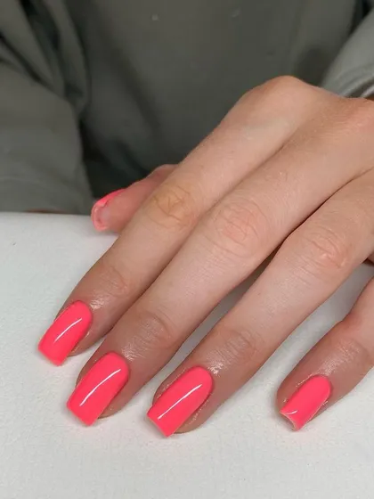 A vibrant, solid coral-pink manicure on perfectly shaped square nails. This is a great example of a simple, bold color making a big impact.