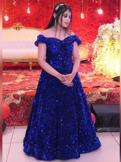 Make a bold statement at any party with this royal blue off-shoulder sequin gown. The vibrant color and sparkling embellishments make it a perfect rental choice for a reception or evening event.