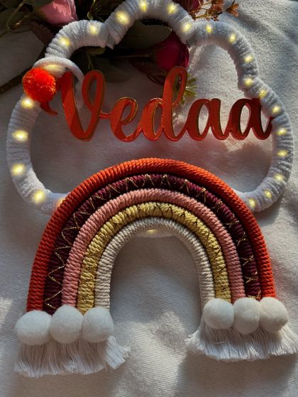 This shot shows the beautiful texture and colors of the "Vedaa" name hanging in natural light. The little pom-pom adds a playful touch.