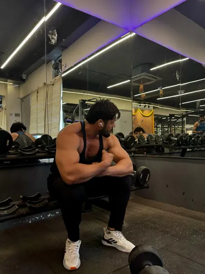 Another angle showing the physique in a seated position, highlighting the arm and shoulder mass.