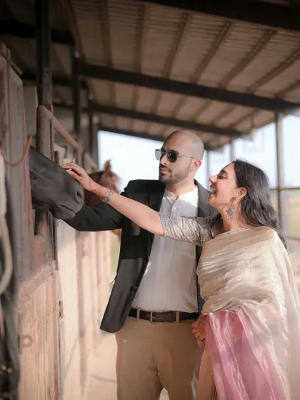 A unique pre-wedding shoot at a stable. This candid moment between the couple and a horse adds a touch of rustic grace and personality to their love story.