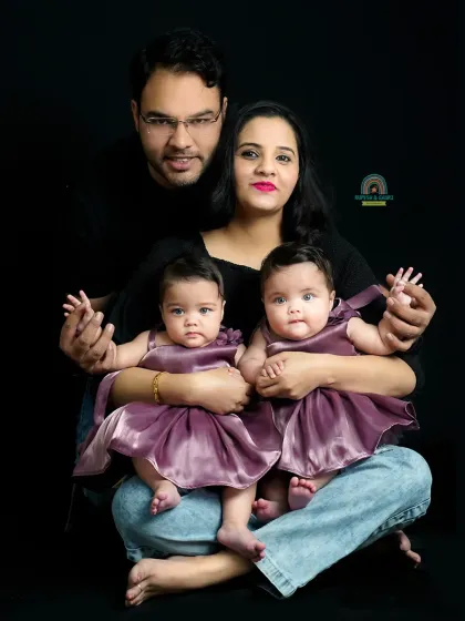 A striking family portrait with twin babies against a simple black backdrop. This style puts all the focus on the family's connection and expressions.