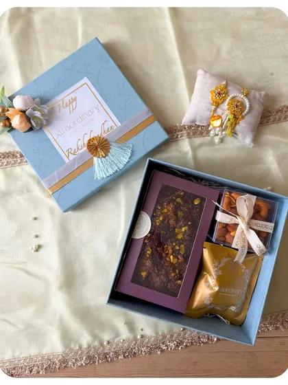 An elegant blue box for Rakhi, containing our signature chocolate bark, gourmet nuts, and a Rakhi set.
