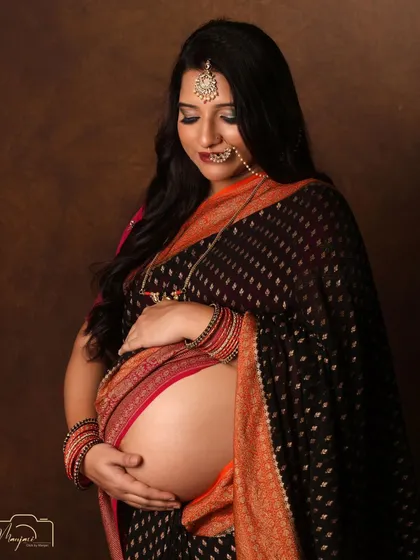 A stunning bare-bump portrait in a black and orange saree. The traditional jewelry completes the look.