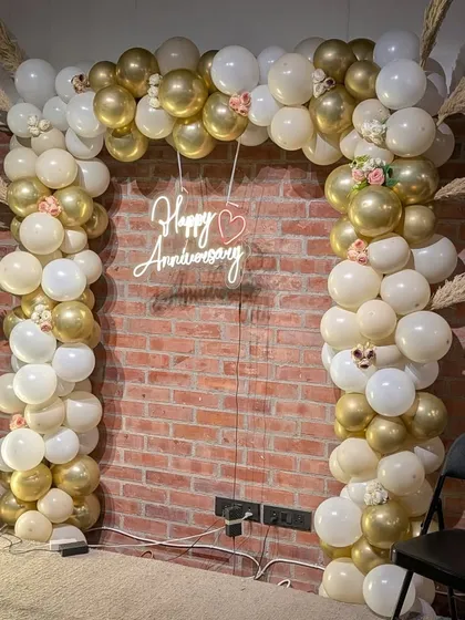 A close-up of the elegant gold, white, and cream balloon arch, accented with pampas grass and small flowers for a rustic-chic anniversary theme.