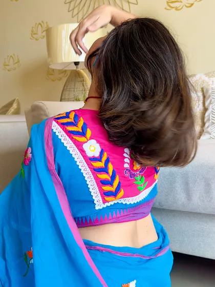 A playful hair flip moment, showing the back of the blouse and the flow of the saree.