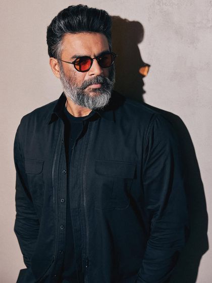 A close-up on the face, where the red glasses provide a striking pop of color against the all-black outfit.