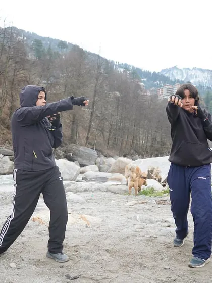 Two participants practicing their shadow boxing form side-by-side. The focus here is on technique and movement, with the Beas river in the background.