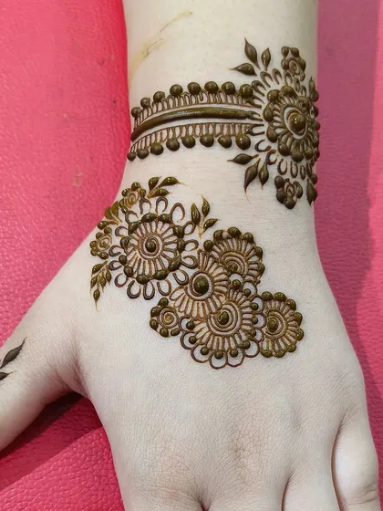 A combination of the floral vine and wristband design. This is a popular choice for guests who want something more than a simple motif but less than a full-hand design.