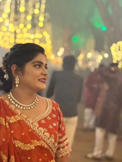 A candid shot of a client at a wedding, wearing our orange bandhani style lehenga and jewellery.