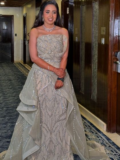 A client in a glamorous gown, her hair in soft waves with a sparkling bow accessory.