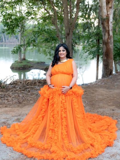 A beautiful lakeside portrait of a mom-to-be in a bright orange gown.