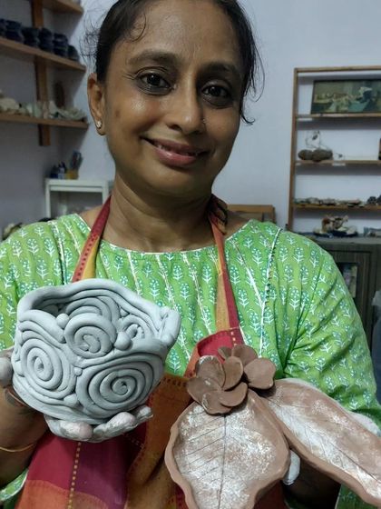 This talented student is showing off her beautiful creations from our workshop. She made a lovely bowl with a swirl pattern and a leaf-shaped dish. It's so rewarding to guide students and see them create things they are proud of.