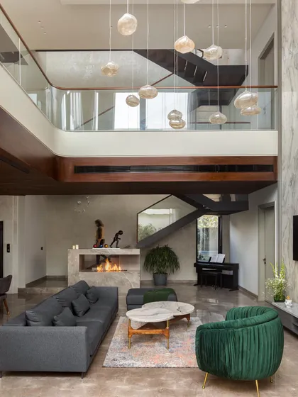 We believe in creating spaces that breathe. This double-height living room, anchored by a modern marble fireplace and cascading pendant lights, is the heart of the home. It’s a testament to our love for grand volumes, natural light, and creating a perfect balance between impressive scale and intimate comfort.
