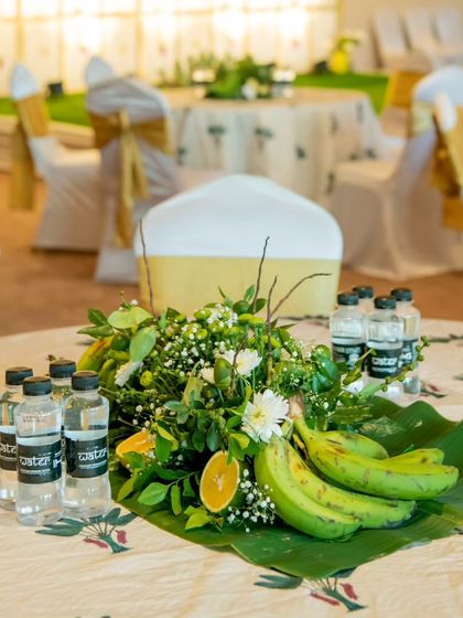 A close-up of a guest table centerpiece made from banana leaves, fresh fruits, and flowers. This natural and tropical-themed decor adds a unique and refreshing touch to the event's ambiance.