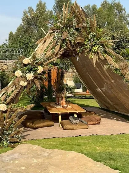 We created this serene boho-chic picnic setup for an outdoor baby shower. It features a draped canopy, low wooden seating with comfortable floor cushions, and arrangements of pampas grass and dried florals for a natural, earthy aesthetic.