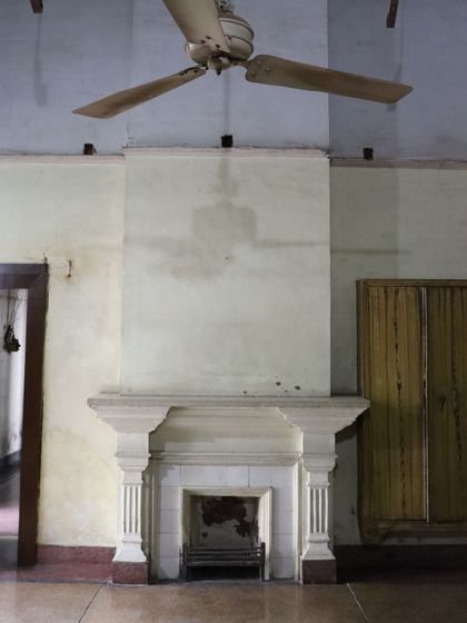 A classic colonial-style fireplace and an old-fashioned ceiling fan, elements that contribute to the unique Indo-European feel of the house.