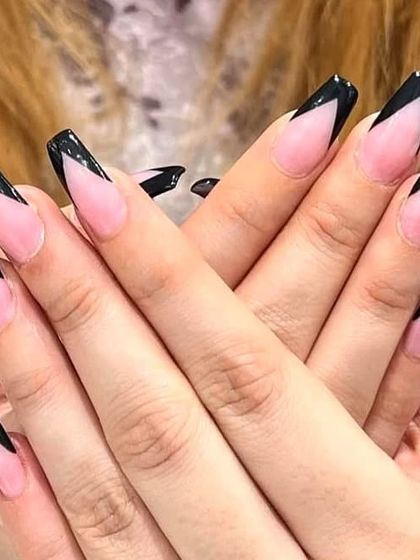 A sharp and dramatic black V-tip French manicure on long coffin nails.