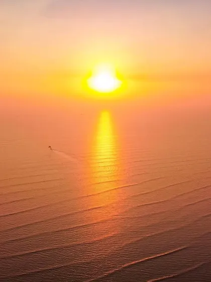 A drone shot of the sunset over the sea in Alibag, where the sun's reflection on the water looks like a lightsaber.