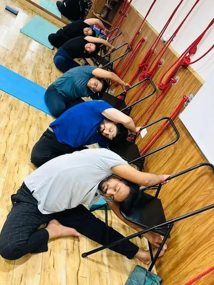Students use chairs to support a deep side bend, stretching the entire side of the body from the hip to the fingertips. This is a great way to improve lateral flexibility of the spine.