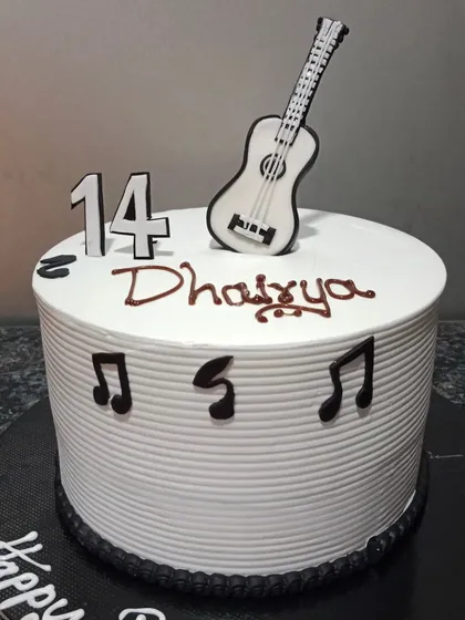 A clean and simple music-themed cake for a 14th birthday. The cake is decorated with a guitar topper and musical notes.