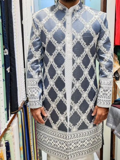 A full view of a client in a grey open sherwani with a white geometric pattern. The design is modern and eye-catching, perfect for a sangeet or reception.