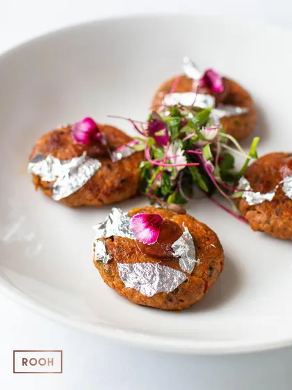 Four perfectly formed Mutton Chapli Kebabs, ready to be shared. This dish is ideal for starting a meal, offering a taste of classic flavours with a refined presentation.