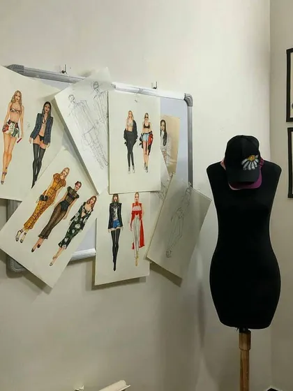 Our classroom walls are often filled with student work, creating an inspiring atmosphere. This image shows a collection of fashion sketches alongside framed illustrations and a mannequin, representing the journey from paper to form.