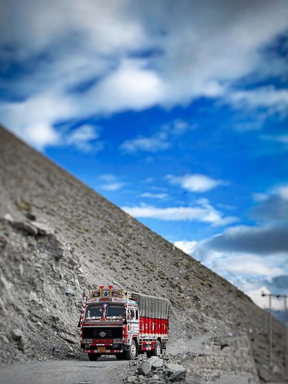 A classic decorated Indian truck navigates a narrow, winding road in Spiti Valley. This image captures the challenging yet beautiful reality of travel in the high Himalayas.