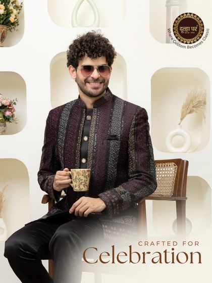 Crafted for celebration. A model enjoys a cup of tea while wearing a deep maroon, textured Bandhgala, showing that style and comfort can go hand in hand.