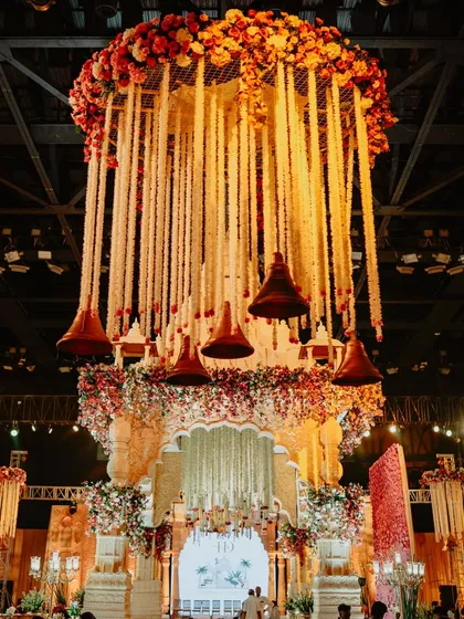 A central hanging installation of florals and traditional bells crowns this majestic mandap, adding another layer of grandeur to the temple-inspired structure.