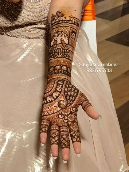 A close-up of a royal bridal mehndi design, showcasing the fine details of peacock and palace motifs on the arm. Every line is drawn with precision to create a piece of wearable art.