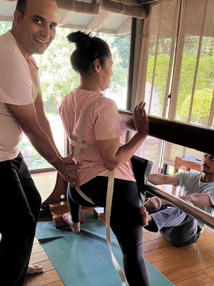 Teamwork is essential in Iyengar yoga. Here, my assistants and I work together to help a student with a supported pose, using belts and the 'horse' prop to ensure stability and correct alignment.