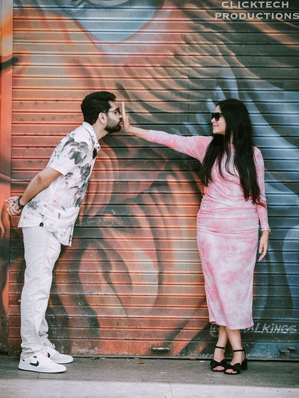A playful and artistic shot of a couple posing against a colorful graffiti wall, adding a cool, urban edge to their pre-wedding photos.