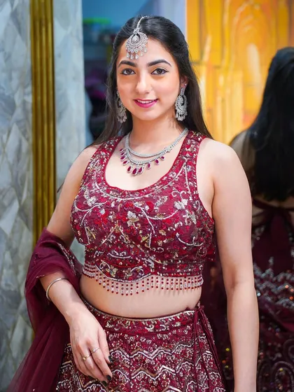 A happy, smiling portrait in a full bridal lehenga look, complete with a maang tikka and matching jewelry.