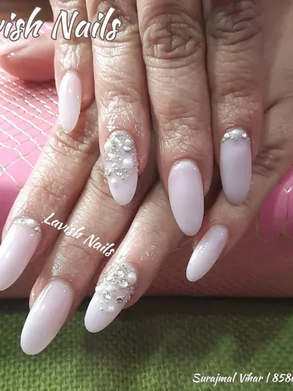 A delicate and angelic look with milky white nails and accent nails adorned with clusters of pearls and rhinestones.