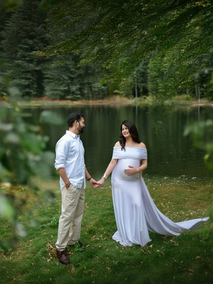 Holding hands by the water's edge. This photo symbolizes their journey together into parenthood, set against a beautiful natural backdrop.