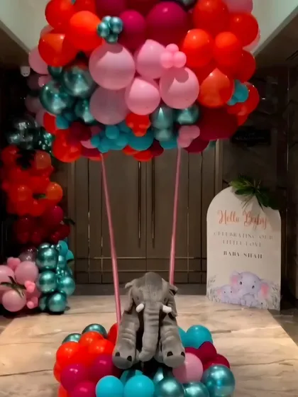 A creative hot air balloon sculpture made of balloons with a plush elephant in the basket, serving as a stunning entrance piece.