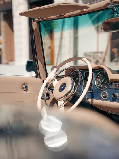 The interior of a classic Mercedes, focusing on the elegant steering wheel and dashboard. This shot captures the craftsmanship and aesthetic of a different time.