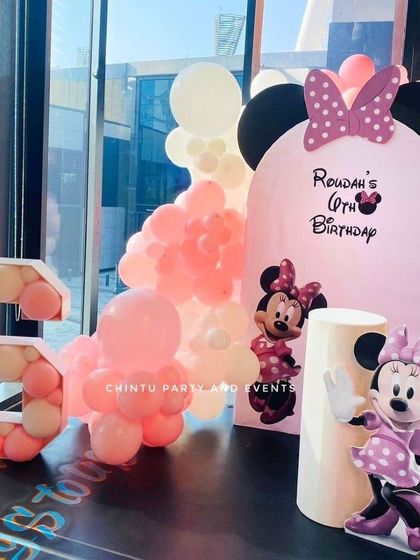 A sweet Minnie Mouse theme for a 6th birthday. This setup includes a Minnie Mouse cutout, a custom pink arched backdrop, and a large balloon-filled marquee number '6'.