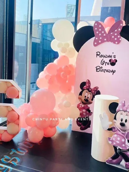 A sweet Minnie Mouse theme for a 6th birthday. This setup includes a Minnie Mouse cutout, a custom pink arched backdrop, and a large balloon-filled marquee number '6'.