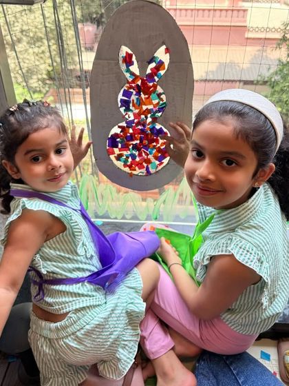 Two sisters working together on a beautiful Easter window craft. They are creating a bunny mosaic using colorful paper pieces.
