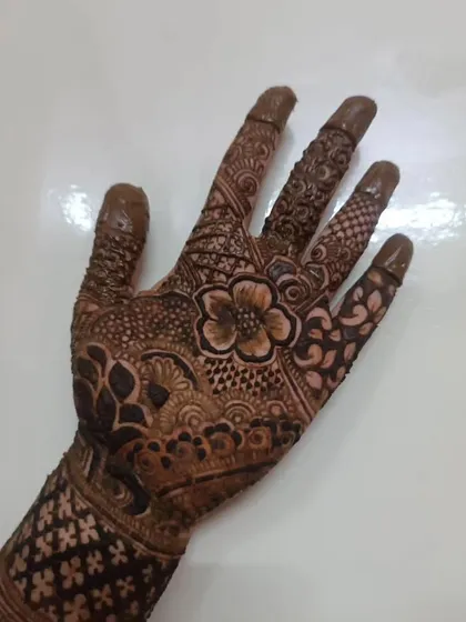The palm of a bridal hand, filled with a central flower and surrounded by intricate patterns. Every finger has a unique, detailed design.