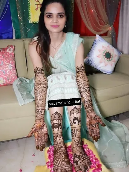 A full bridal look for a happy bride, with her hands and feet covered in a cohesive design featuring wedding processions and elephant motifs.