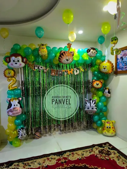A fun Jungle theme birthday decoration featuring a green balloon arch decorated with various animal foil balloons. This setup is perfect for creating a wild adventure right in your living room.