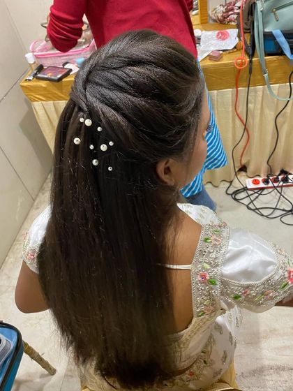 A half-up hairstyle on crimped hair, decorated with scattered pearls for a touch of elegance.