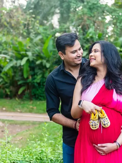 A sweet couple's portrait. The mom-to-be holds a pair of tiny yellow shoes, a hint of the sunshine their baby will bring.